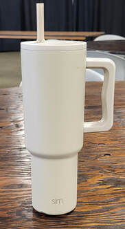 A tall, white thermal mug with a straw.